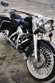 Close-up of a vintage black cruiser motorcycle with chrome details parked on a concrete surface.