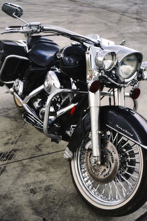 Free Close-up of a vintage black cruiser motorcycle with chrome details parked on a concrete surface. Stock Photo