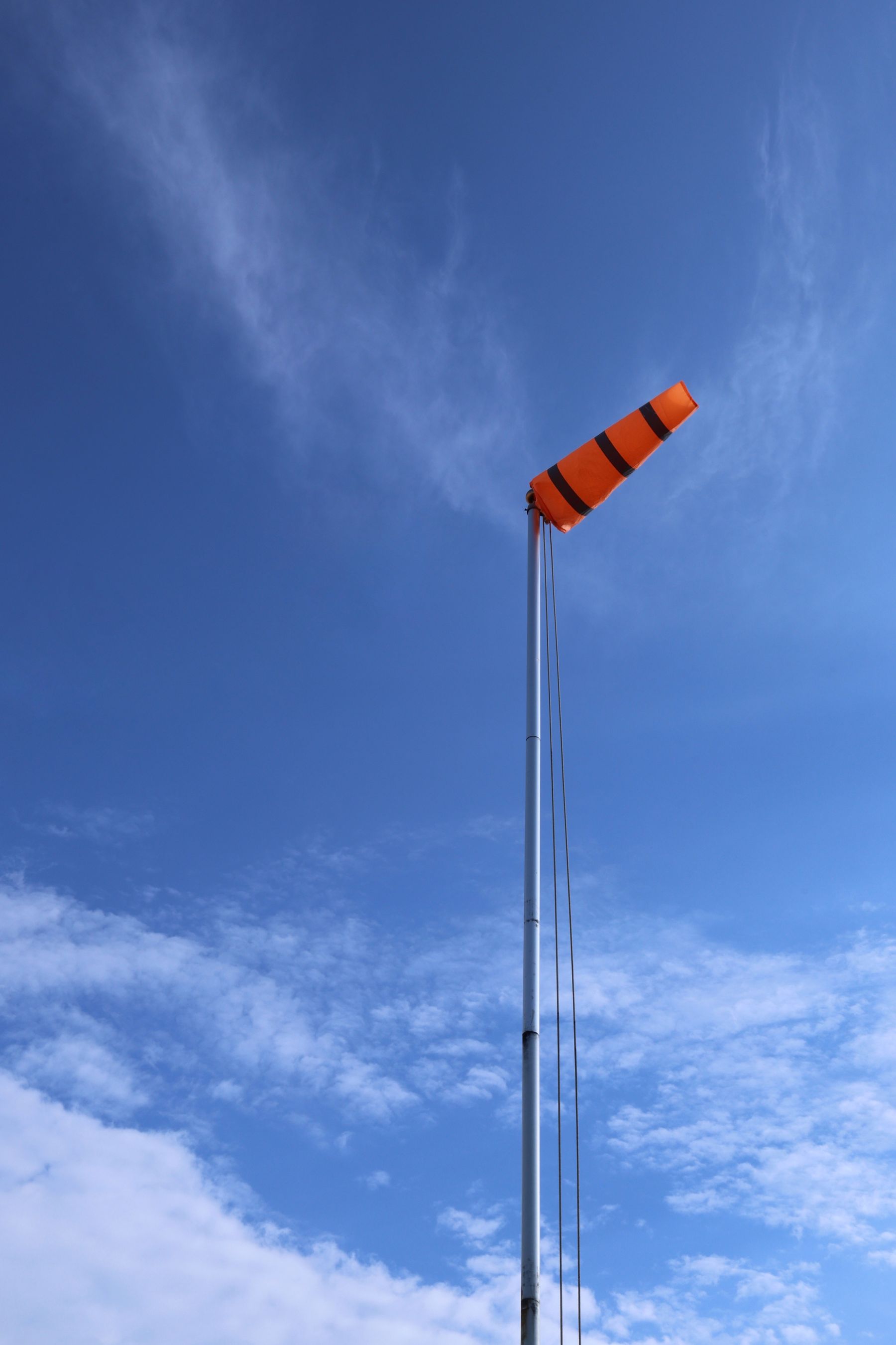 An orange windsock against a blue sky