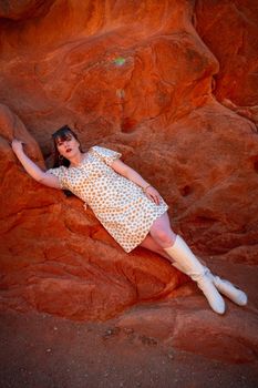 Fashionable woman in spring outfit posing against natural red rock backdrop.