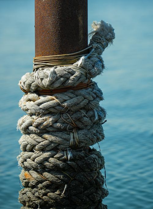 Free Detailed view of a weathered rope wrapped around a rusty pole by the water in Denmark. Stock Photo