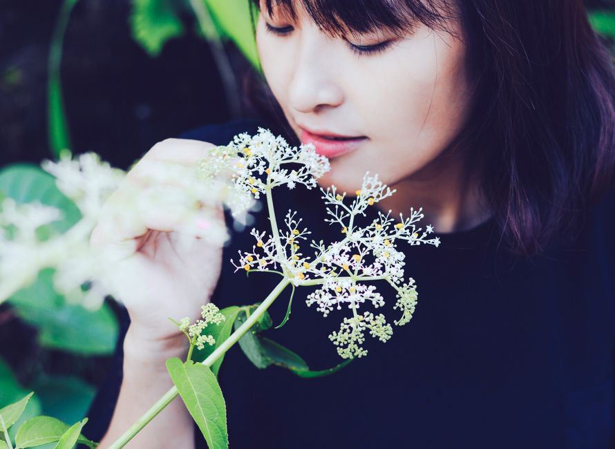 晴れた日の屋外で花の自然の美しさを鑑賞する穏やかな女性。