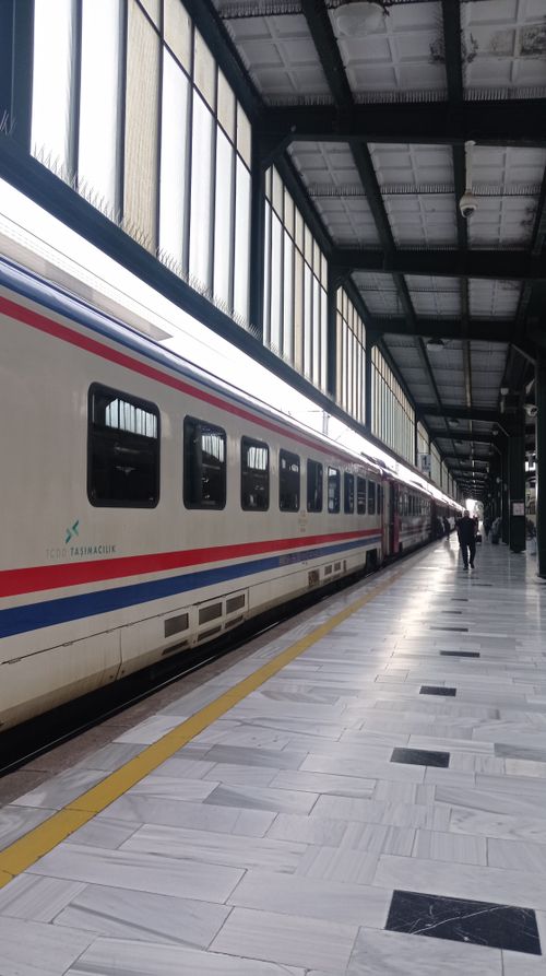Free Long view of a modern train station platform with a departing train and an individual walking along Stock Photo
