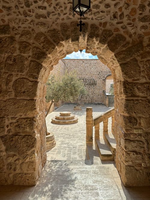 Free Explore the rustic beauty of an ancient stone courtyard through a historic arched entryway. Stock Photo