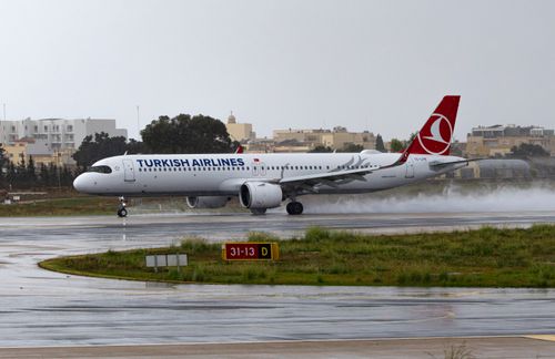 Free Turkish Airlines jet touching down on a rainy runway, showcasing aviation in action. Stock Photo