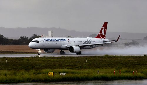 Free Turkish Airlines Airbus A321 landing on a rainy runway, emitting water mist. Stock Photo