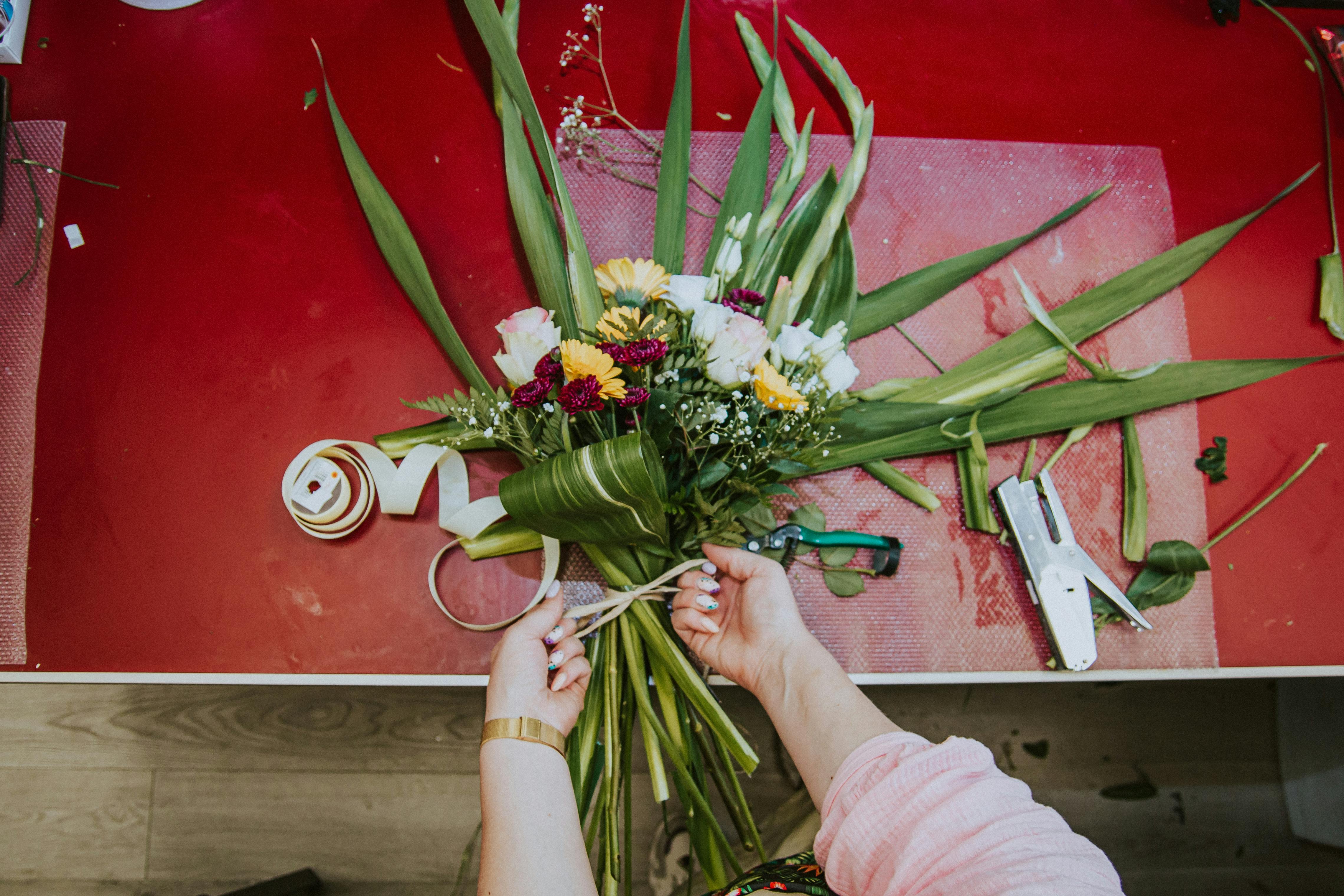 A florist skillfully arranges a colorful bouquet in a workshop in Poland.