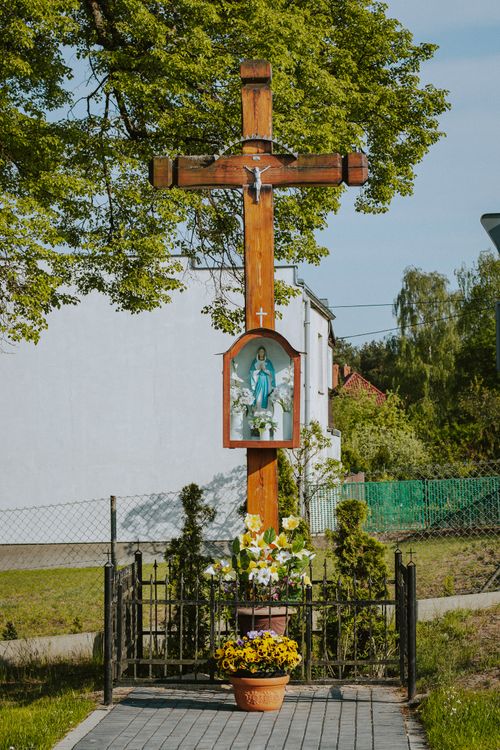 Free Outdoor wooden crucifix with Holy Mary image and floral arrangements in Ocypel, Poland. Stock Photo