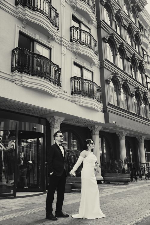 Free Stunning black and white photo of a bride and groom in a cityscape, showcasing elegant architecture. Stock Photo