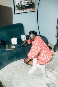 Person in pink robe recording podcast in cozy home environment with laptop and microphone.