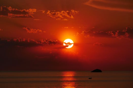 Beautiful sunset with vibrant orange colors, clouds, and gentle sea waves.