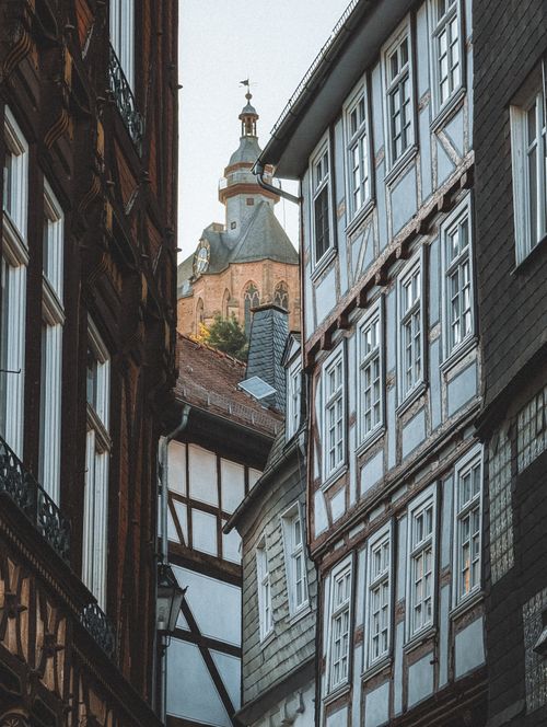 Free Discover the traditional half-timbered buildings lining a narrow street in Marburg, Germany, with a historic church in the background. Stock Photo