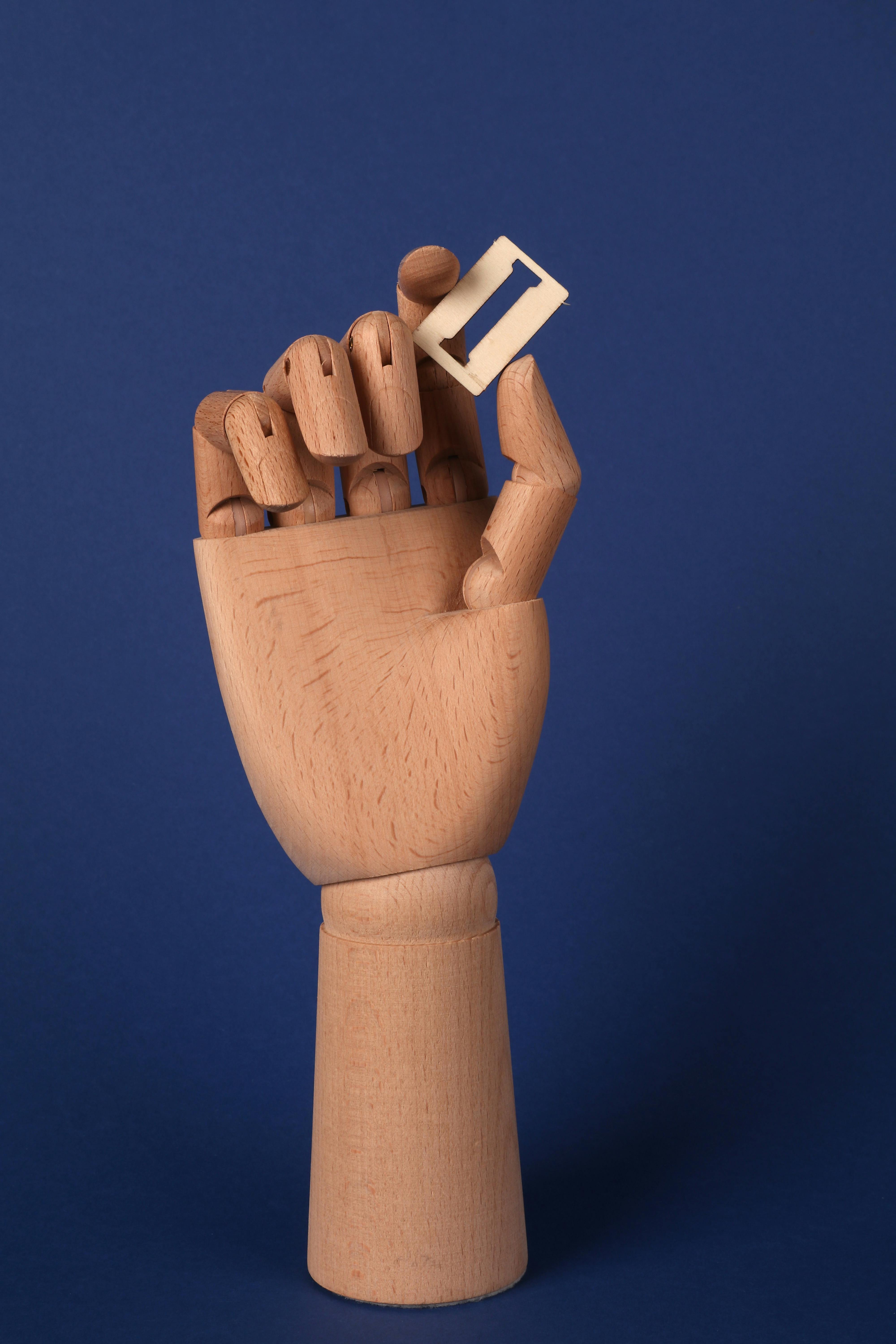 무료 나무 마네킹 손이 파란색 배경에 문자 I가 적힌 블록을 잡고 있습니다. 스톡 사진