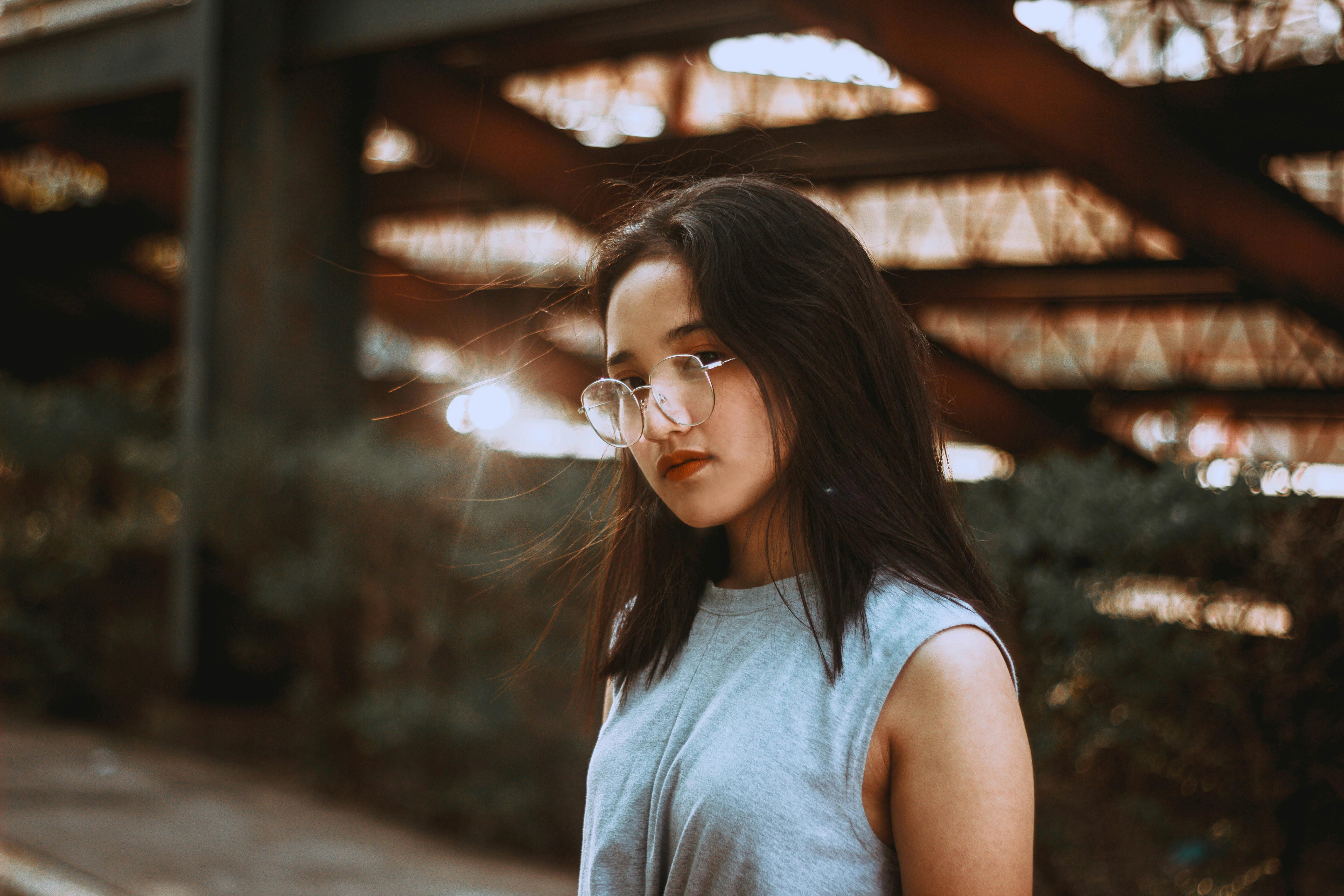 在户外柔和的晚光中，一位时尚的年轻女子戴着眼镜