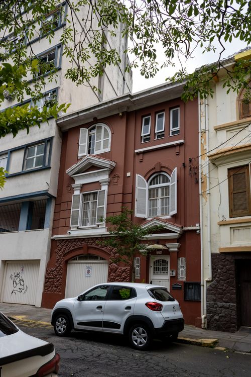Free A charming brown townhouse with white windows and a car parked in front, captured in an urban setting. Stock Photo