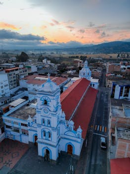 A stunning aerial shot of a historic church in a city at sunrise with a vibrant sky.