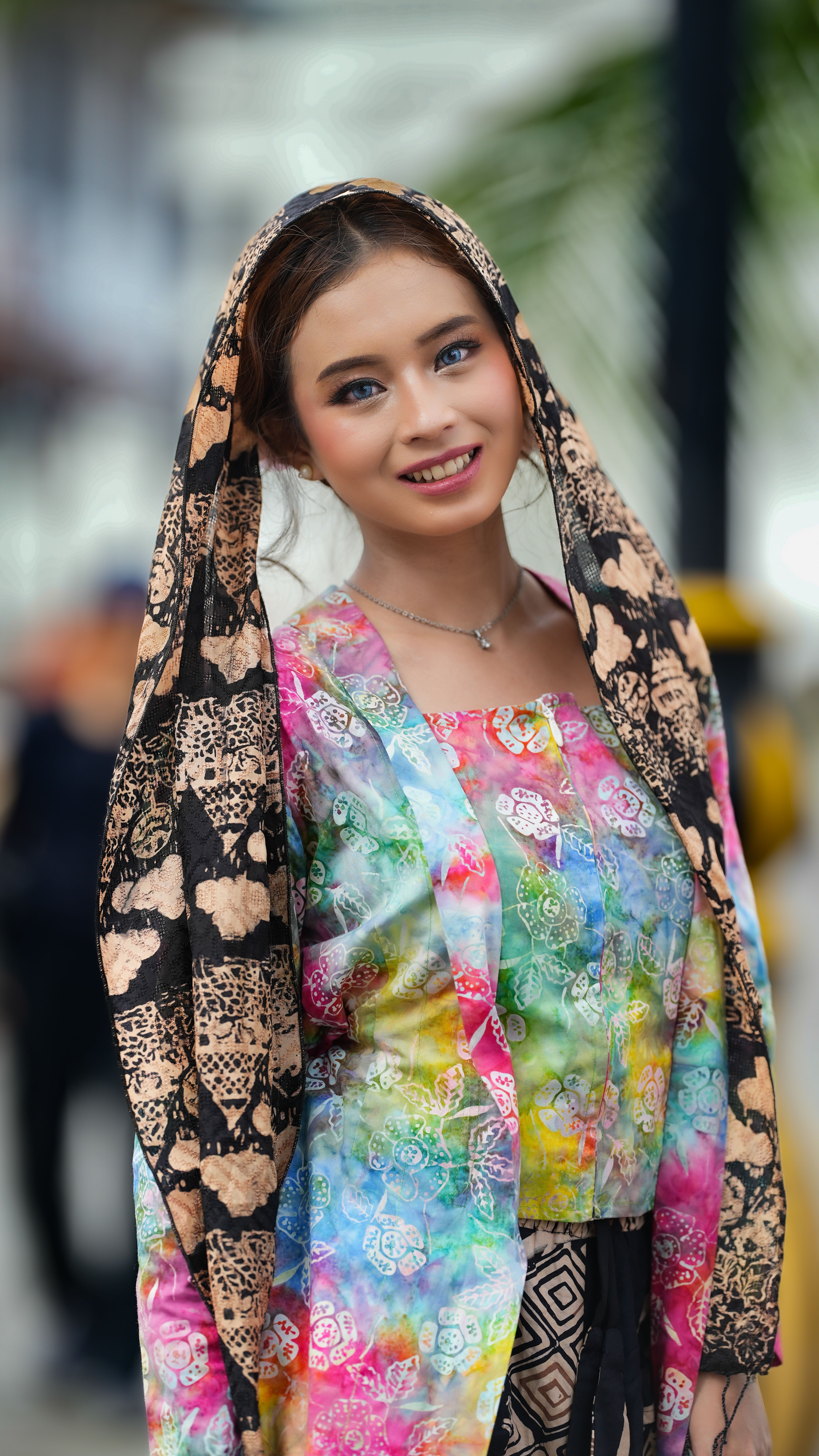 Portrait of a woman in multi-colored batik outfit with a smiling expression in Jakarta, Indonesia.