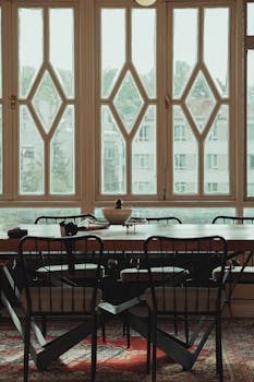 A stylish dining area with large diamond-patterned windows and elegant furniture.