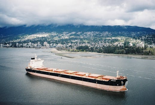 Moody aerial view of a cargo ship in Vancouver's harbor under overcast skies.