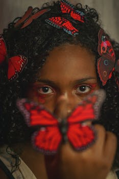 Close-up of a woman adorned with vivid red butterfly decorations in her hair.