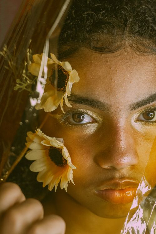 Free Close-up portrait of a person with sunflowers, creating an artistic and vibrant composition. Stock Photo