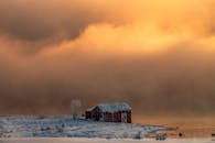 雾蒙蒙的河流和金色的日落天空映衬着风景如画的冬季谷仓