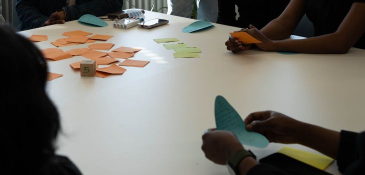 Team members in a collaborative meeting with colorful notes at a table, fostering creativity and planning.
