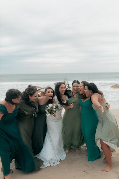 Free Joyful bridal party in green dresses at a beach wedding, celebrating with laughter. Stock Photo