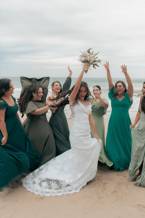 Free Joyful bride celebrates with bridesmaids on a beautiful beach, capturing a lively and festive moment. Stock Photo