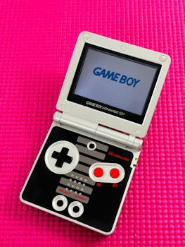 Top view of a Game Boy Advance SP with retro design on a pink surface.