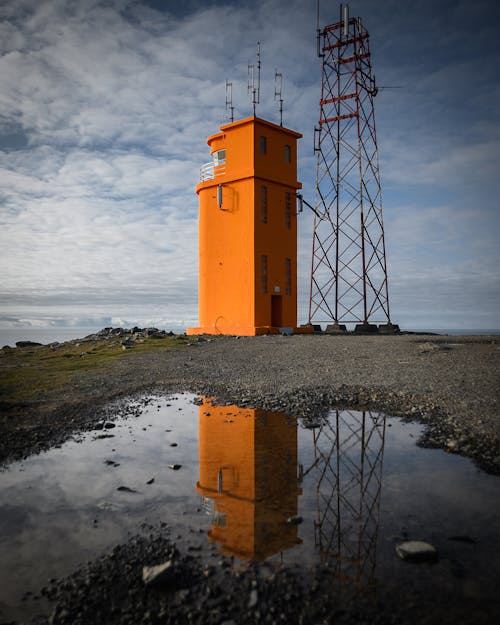 日中の金属塔の横にあるオレンジ色の塔