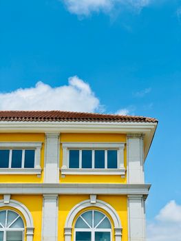 Bright yellow building facade with arched windows against a clear blue sky.