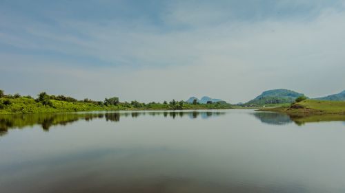 Free Tranquil river scene in India with lush greenery and mountains reflecting in the water. Stock Photo