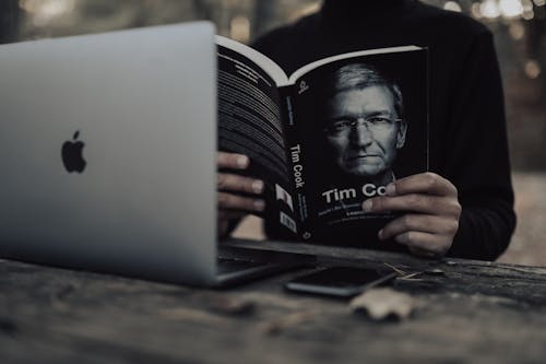 Crop man with laptop reading book