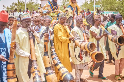 Musicians in colorful attire playing traditional instruments at a Nigerian festival.