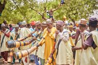 Group of African musicians playing traditional horns in a vibrant outdoor setting.