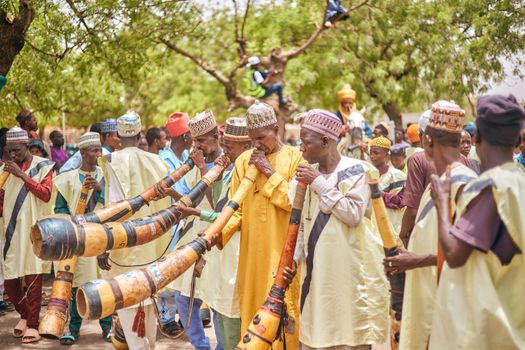 Group of African musicians playing traditional horns in a vibrant outdoor setting.