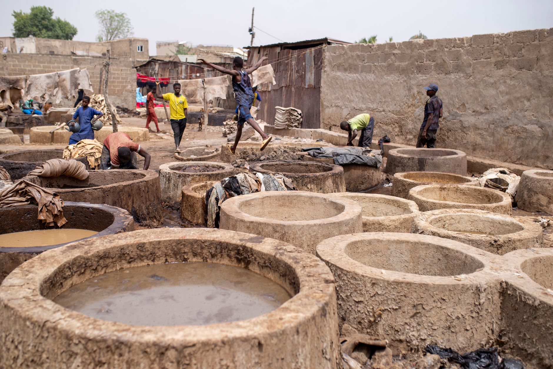 Workers using traditional methods in large clay tanning vats for leather processing.