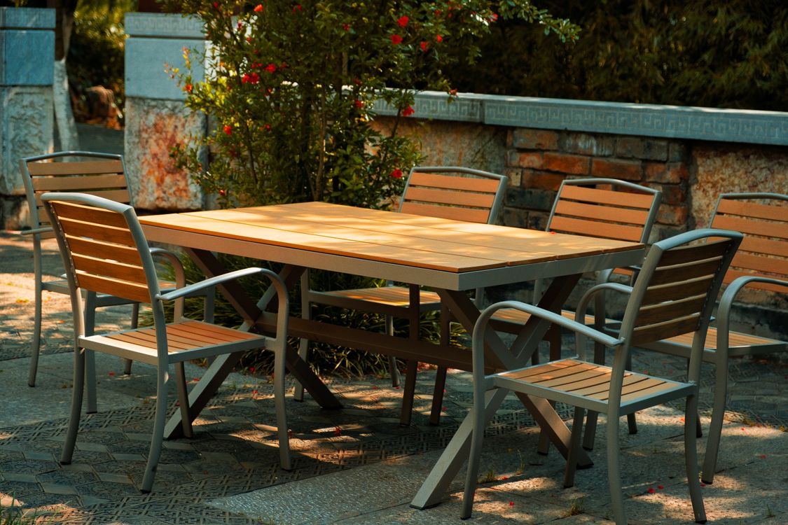 Mesa de madeira com cadeiras disposta em um jardim sombreado