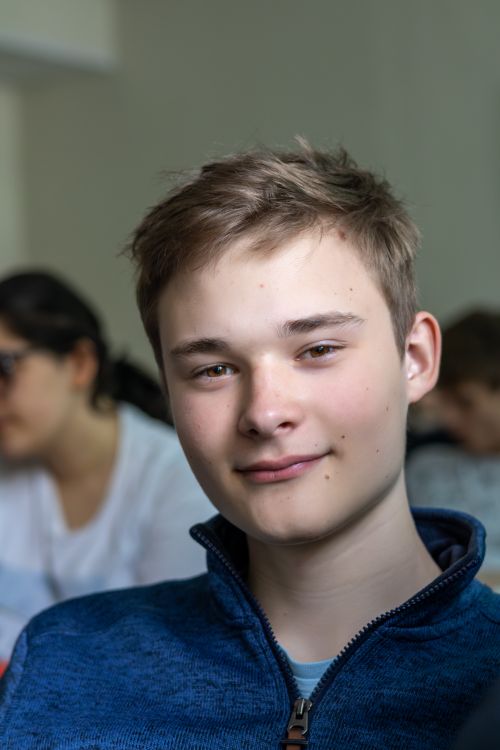 Free Close-up portrait of a smiling teenage boy indoors, casual setting. Stock Photo