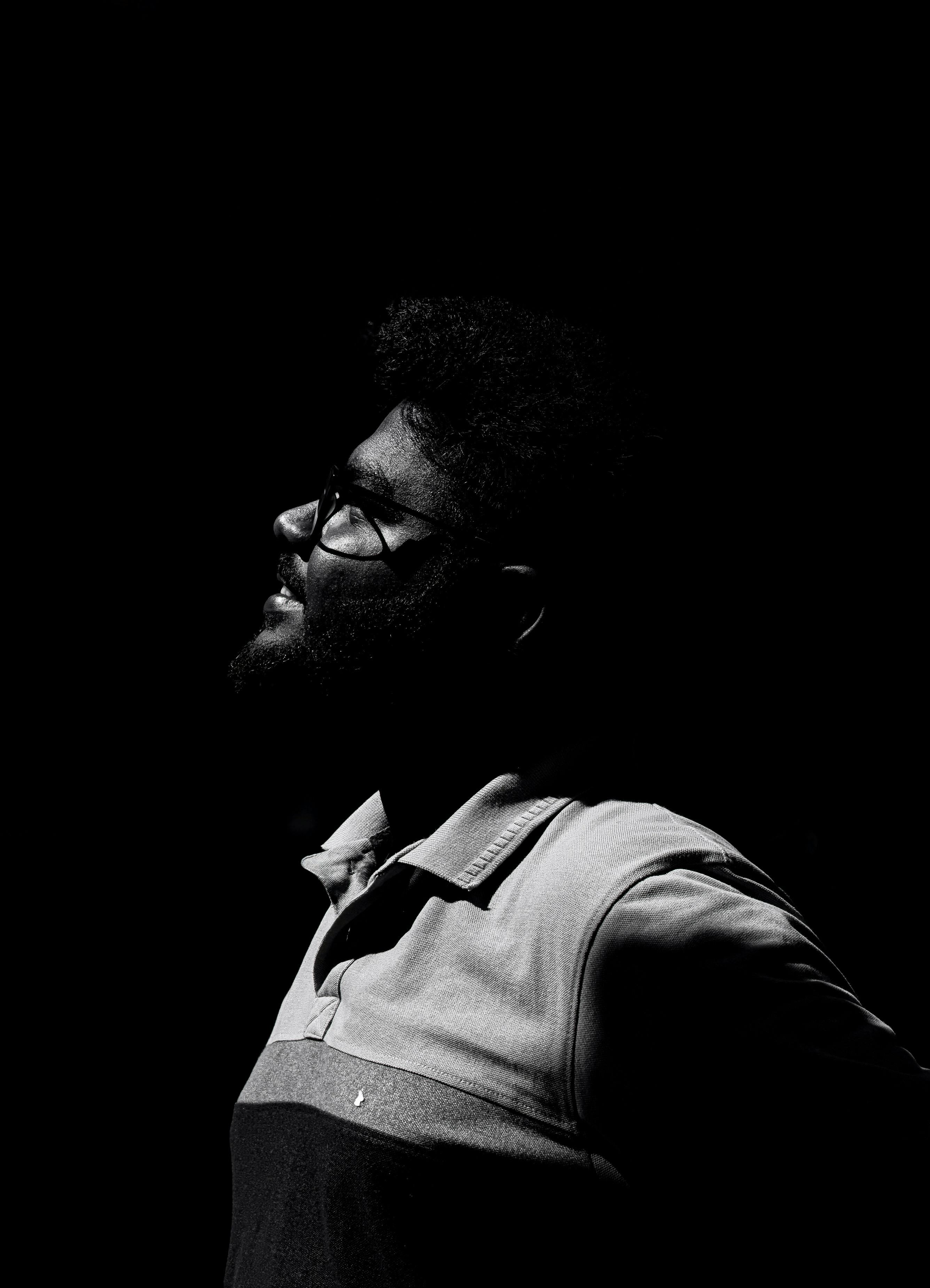 High contrast black and white portrait of a person in profile with glasses, creating a dramatic silhouette effect.