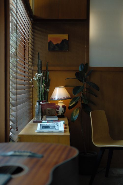 Free Peaceful indoor corner with guitar, plants, and cozy lighting. Stock Photo
