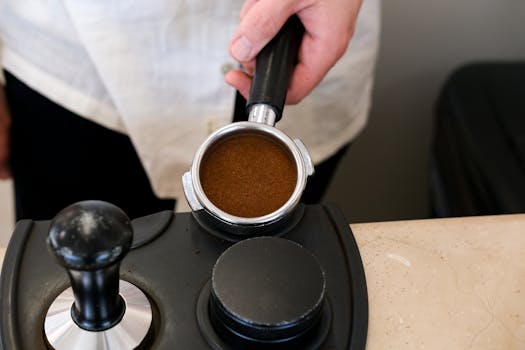 Close-up of a barista preparing espresso, showcasing the portafilter and tamper.