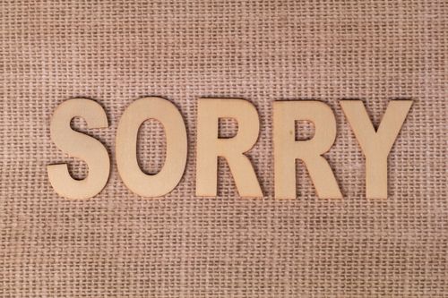 Free Wooden letters forming the word 'sorry' on a burlap fabric background. Stock Photo