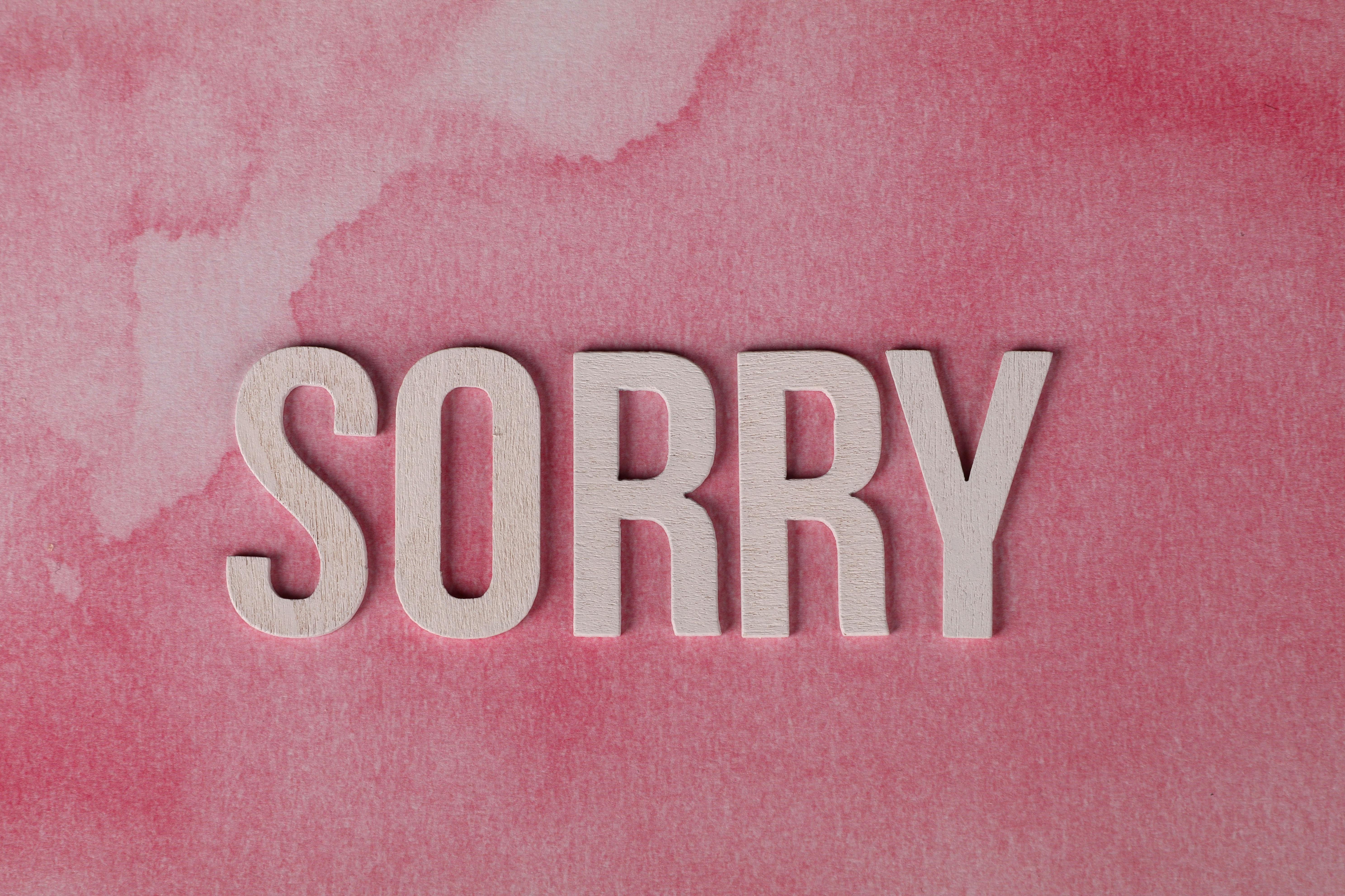 The word 'Sorry' displayed on a pink watercolor textured background, expressing an apology.