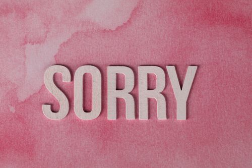 Free The word 'Sorry' displayed on a pink watercolor textured background, expressing an apology. Stock Photo