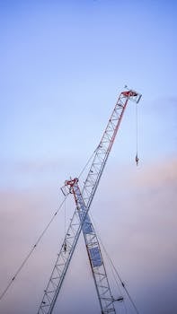 Silhouette of a crane reaching into the blue sky at sunset, showcasing construction themes.