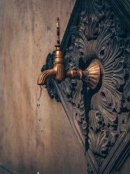 An ornate bronze tap on a decorative vintage background, dripping water.