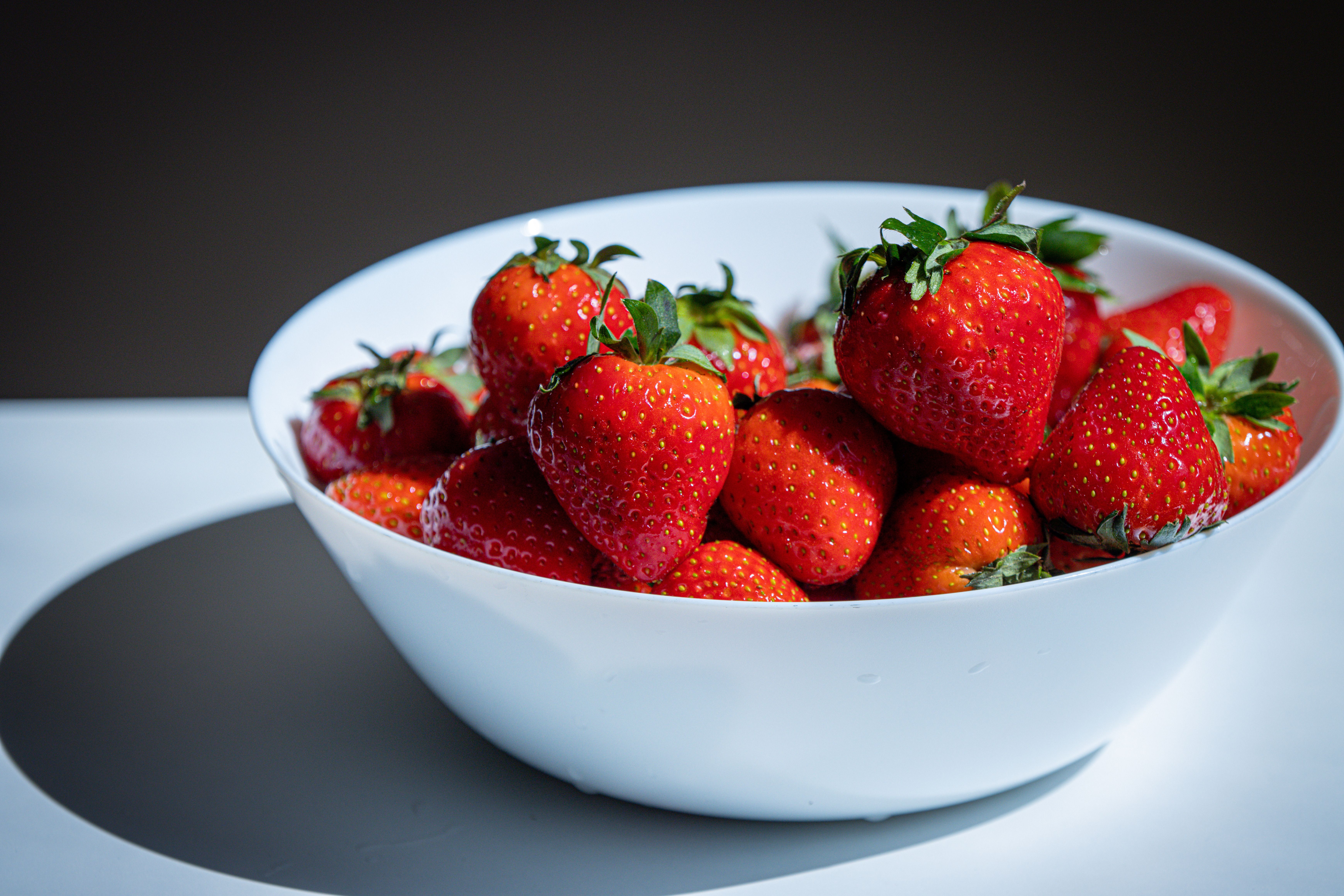 Fresh strawberries rinsing under cold water in a kitchen sink