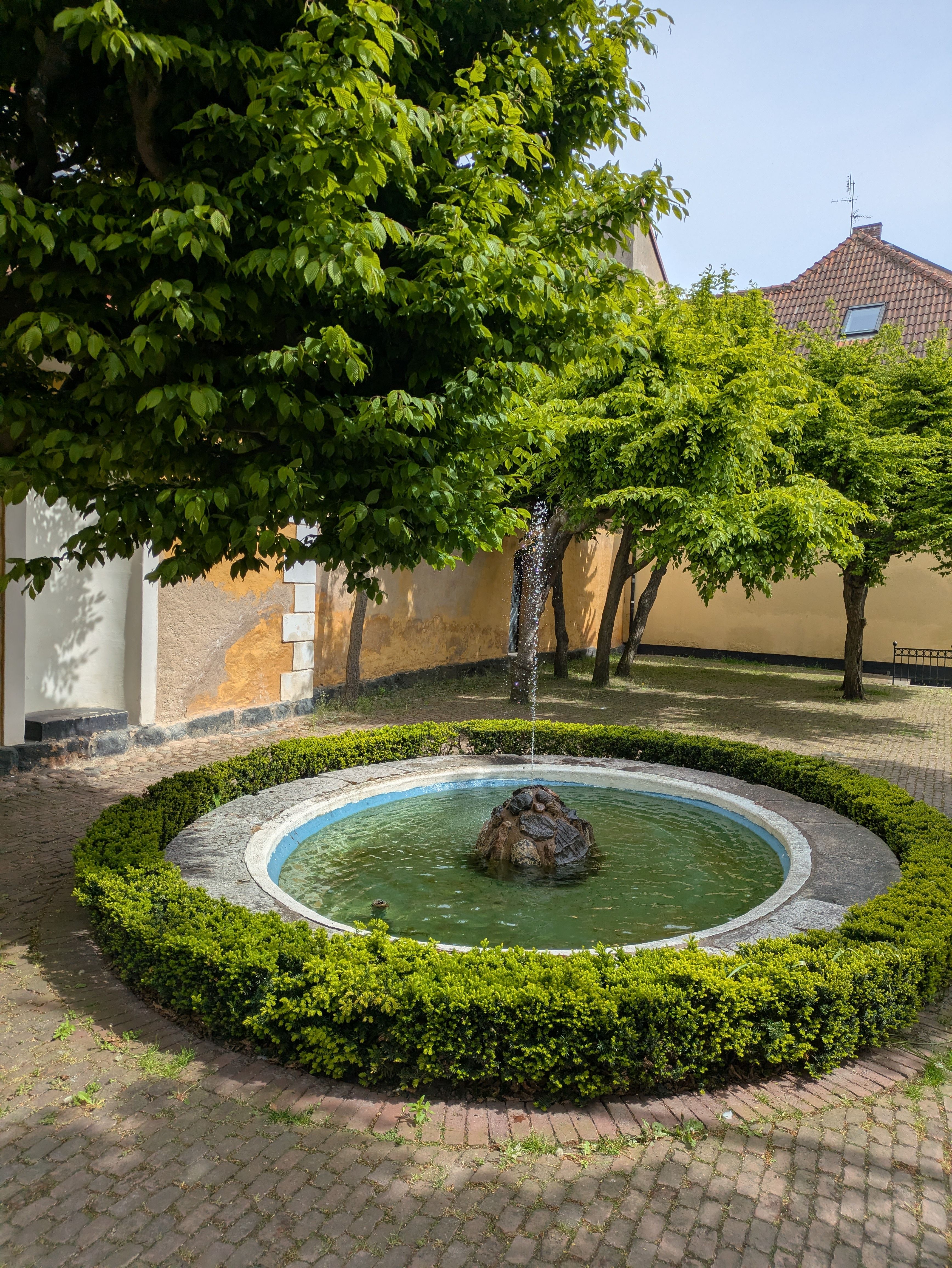 Serene Courtyard Fountain with Lush Greenery · Free Stock Photo
